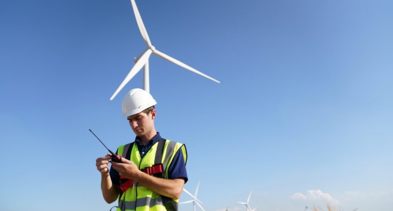 Technician using a walkie-talkie in a wind farm.