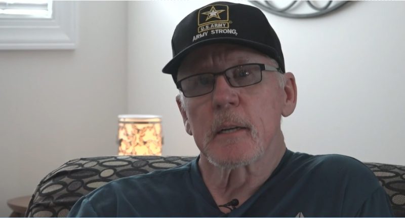 Man wearing glasses and a U.S. Army hat speaks.