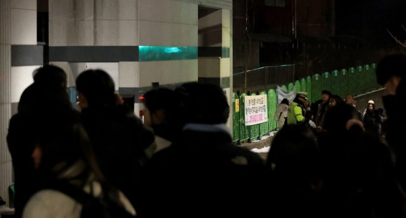 People gathered outside a South Korean elementary school at night following a student's death.
