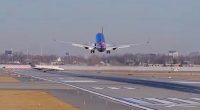 Airplane taking off on a runway with a smaller plane in the foreground.