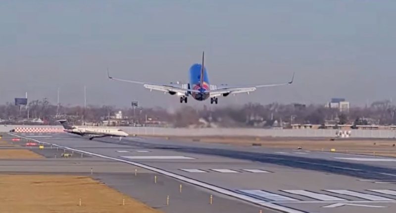 Airplane taking off on a runway with a smaller plane in the foreground.