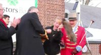 Groundhog Day incident; a woman appears to be rescuing a groundhog from a man in a red coat.