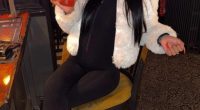 A woman sitting on a bar stool, holding a drink.