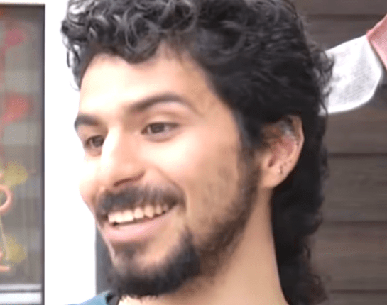 Smiling man with curly dark hair.
