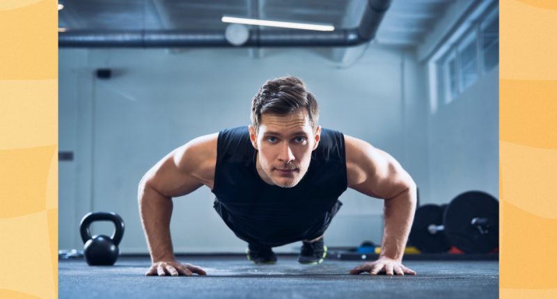 man doing pushups in a dark gym