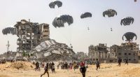 People rush to collect humanitarian aid packages dropped by parachute in a war-torn area.