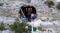 Man standing in the entrance of a cave dwelling.