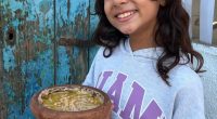Girl holding a frying pan of food.