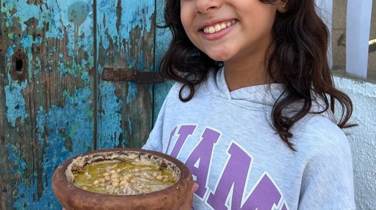 Girl holding a frying pan of food.