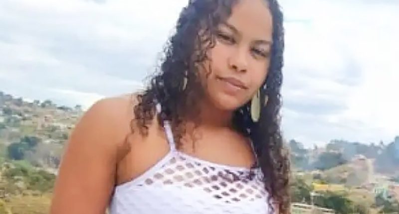 Woman with curly hair wearing a white mesh top.