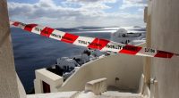 Red and white police tape across a street overlooking the sea in Santorini, Greece.