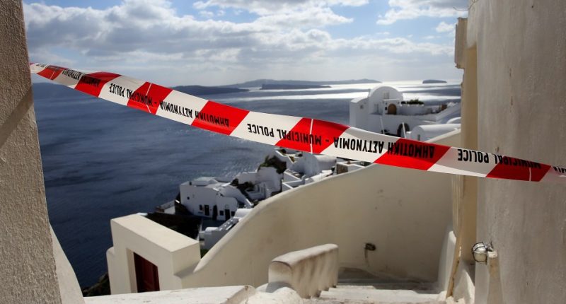 Red and white police tape across a street overlooking the sea in Santorini, Greece.