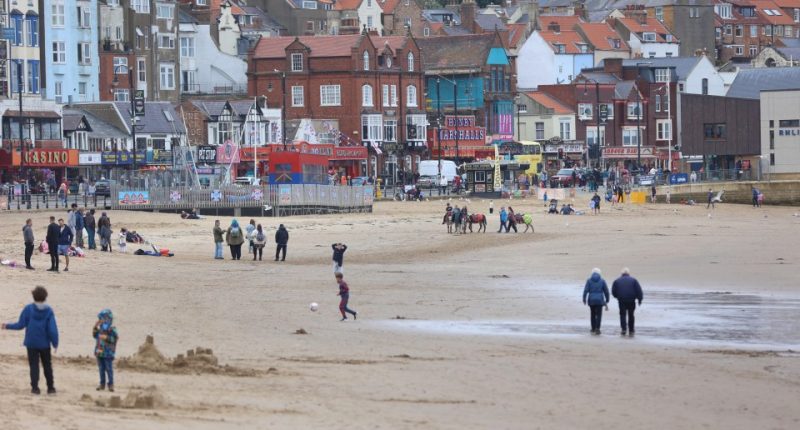 People on a beach in front of buildings.
