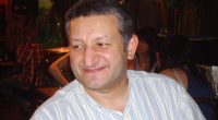Man in striped shirt smiling.