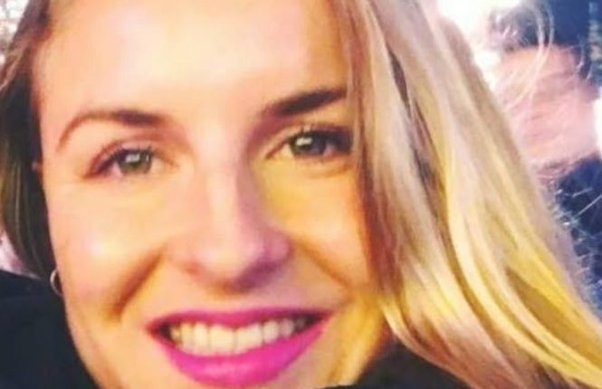 Close-up portrait of a woman with long blonde hair and pink lipstick.