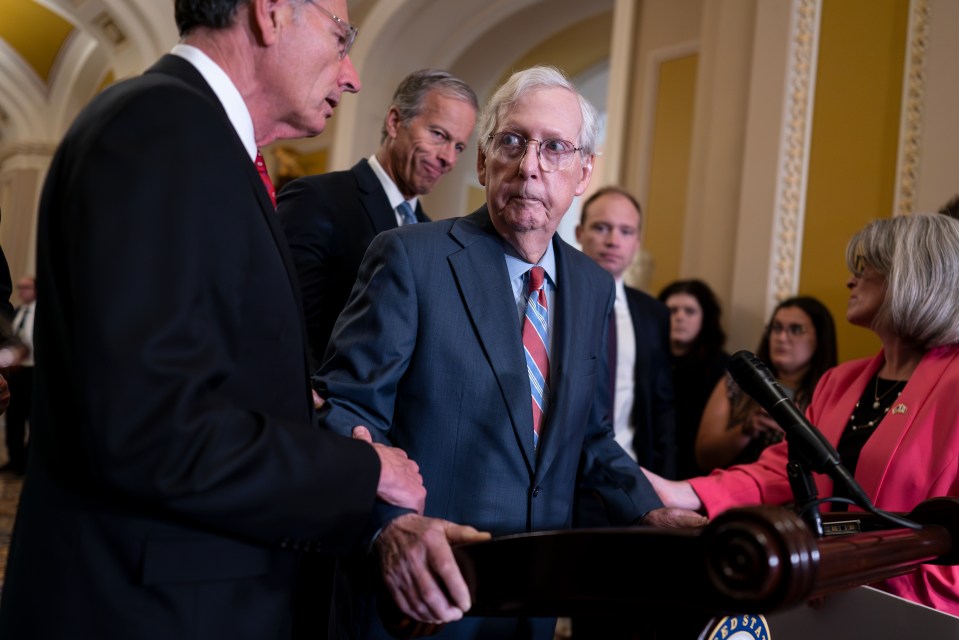 Senate Minority Leader Mitch McConnell being assisted by colleagues.