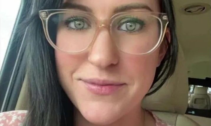 Woman with dark hair wearing glasses in a car.