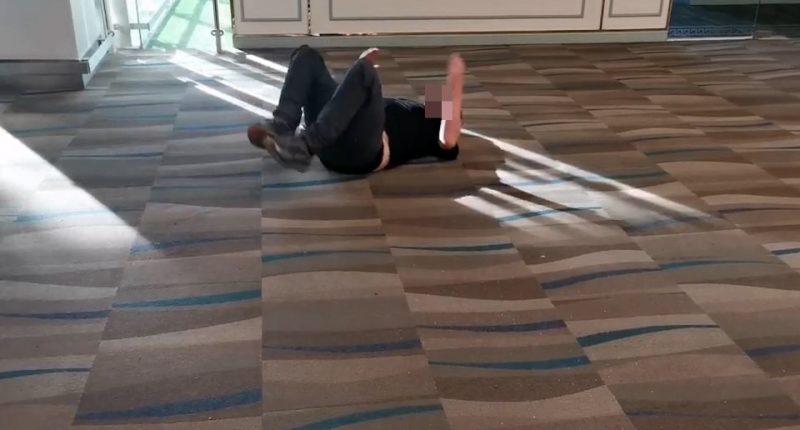 Man lying on airport floor after allegedly dropping cocaine.