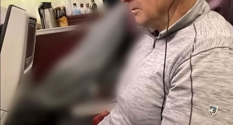 Man wearing headphones sits on airplane.