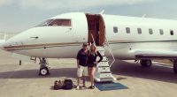 Couple standing in front of a private jet.