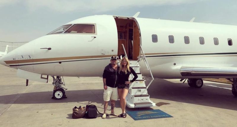 Couple standing in front of a private jet.
