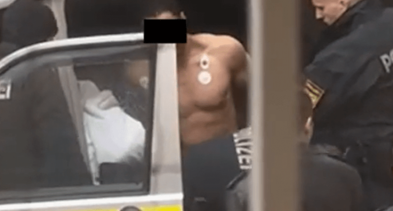 Shirtless man being arrested by police.
