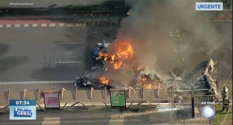 Burning wreckage of a plane crash on a roadway.