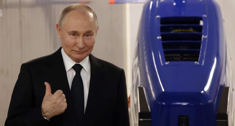 Vladimir Putin giving a thumbs-up at a military plant.