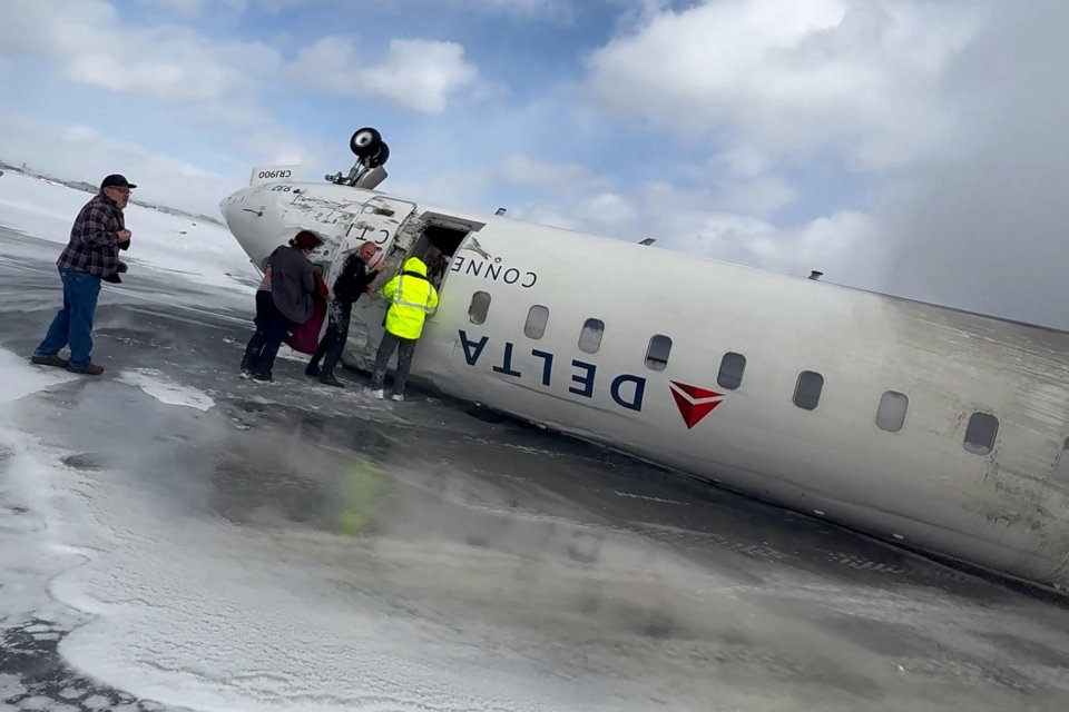 Passengers exiting a crashed Delta Air Lines CRJ-900 jet on an icy runway.
