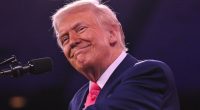 Donald Trump smiling at a microphone.