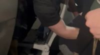 Passengers subduing a disruptive passenger on an airplane.