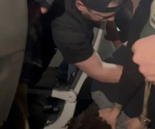 Passengers subduing a disruptive passenger on an airplane.