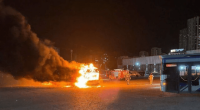 A bus on fire with firefighters responding.