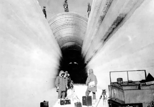 Black and white photo of people near an ice tunnel.