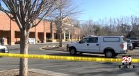 Police vehicle at a Harris Teeter grocery store parking lot, behind police tape.