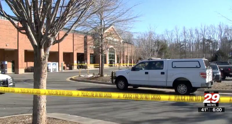 Police vehicle at a Harris Teeter grocery store parking lot, behind police tape.
