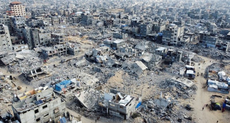 Drone view of destroyed buildings and Palestinians walking amidst rubble in Khan Younis, Gaza Strip.