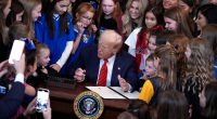 President Trump signing an executive order surrounded by girls.