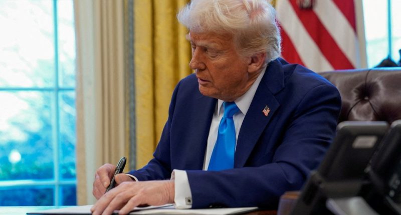 President Donald Trump signing a document in the Oval Office.