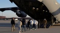 Detained migrants being escorted onto a military aircraft.