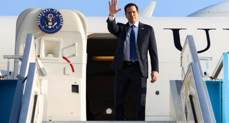 Secretary of State Marco Rubio waving goodbye from an airplane.
