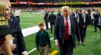 Donald Trump walking on a football field with his grandson.