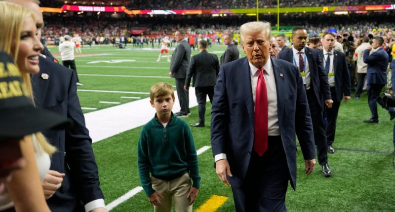 Donald Trump walking on a football field with his grandson.