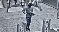 Surveillance image of a suspect holding an assault rifle at a train station.