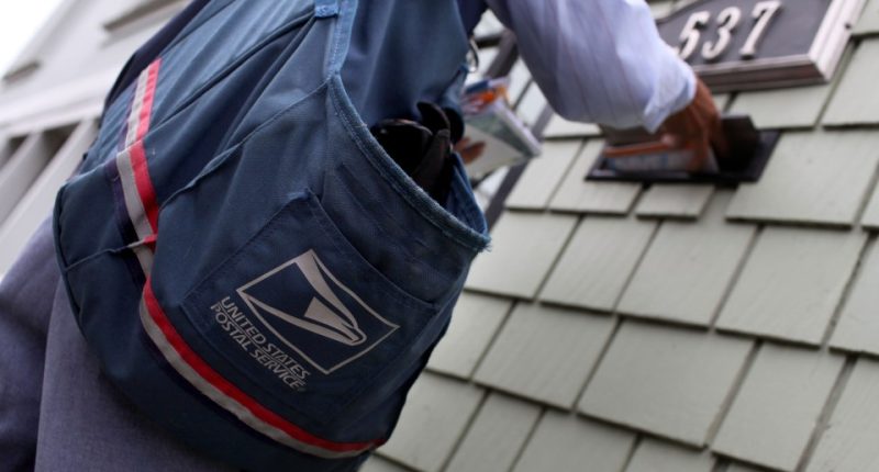 US Postal Service carrier placing mail in a mailbox.
