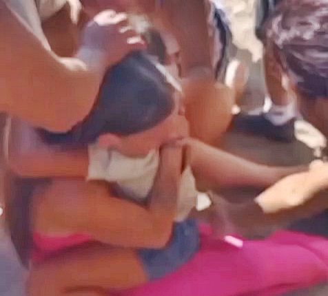 A rescued girl being comforted by her mother and others after being abducted.