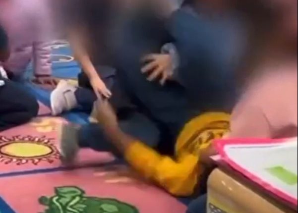Blurred image of children on a classroom floor.
