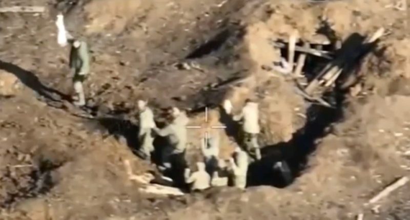 Aerial view of a Russian military unit surrendering to Ukrainian forces in a trench.