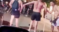 Three shirtless men arguing on a street at night.
