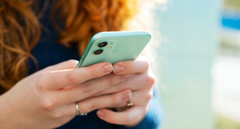 Woman using a mint green smartphone.